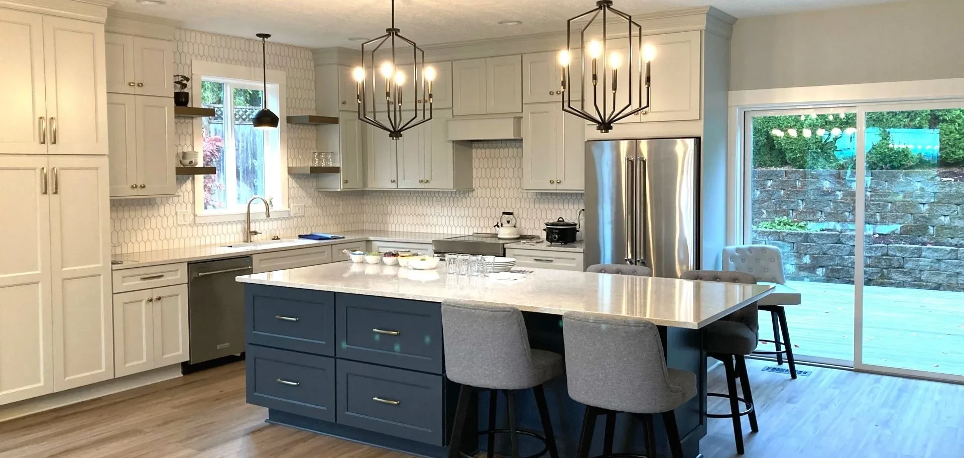 Modern kitchen remodel in Portland featuring white cabinetry, a blue island, pendant lighting, and sliding glass doors.